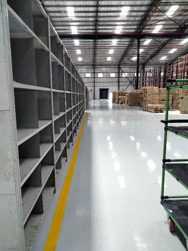 Smooth, high-gloss resin rich floors with light grey warehouse epoxy flooring and yellow safety line markings.