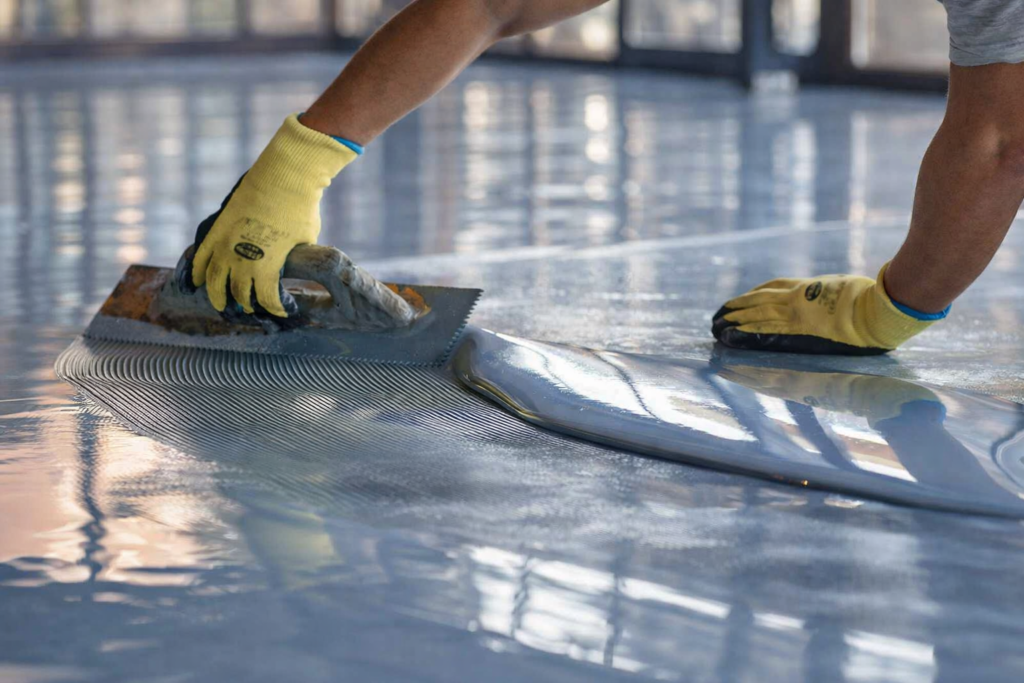 Contractor applying epoxy coating during epoxy floor repair and recoating process in Melbourne commercial space