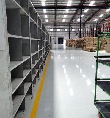 Smooth, high-gloss resin rich floors with light grey warehouse epoxy flooring and yellow safety line markings.